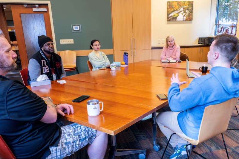 Participants in a SMART-facilitated meeting huddle around a meeting table.